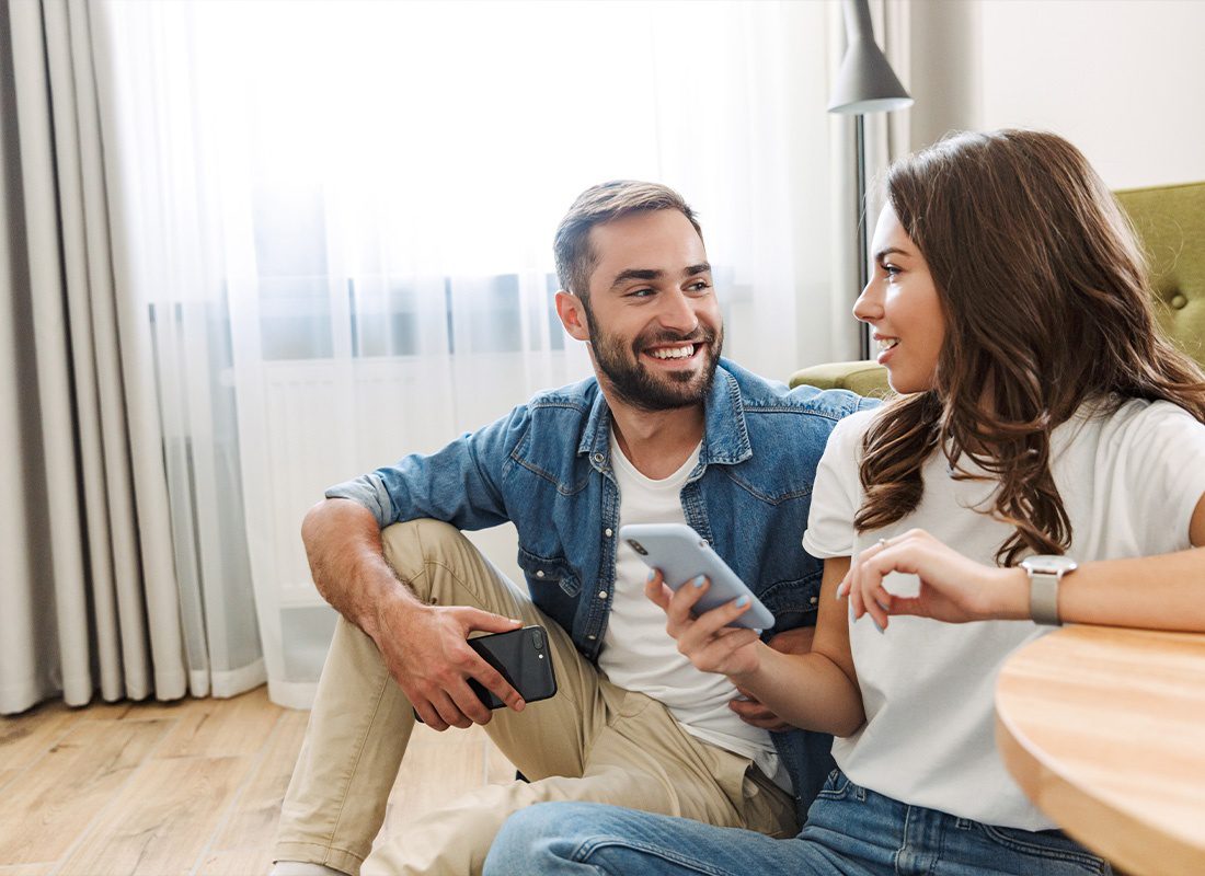 Read Our Reviews - Young Couple Smiling While Looking at a Smartphone